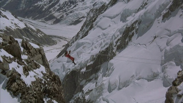 在犹他州，一名登山者用绳子和滑轮拉着自己穿过两座雪山的山峰。视频素材