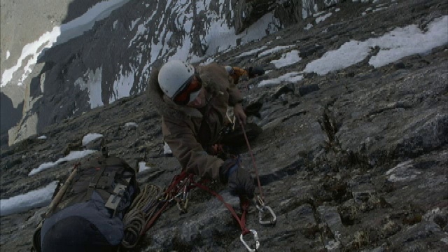在犹他州的山上，一名登山者将一根绳子系在一面岩壁上。视频素材