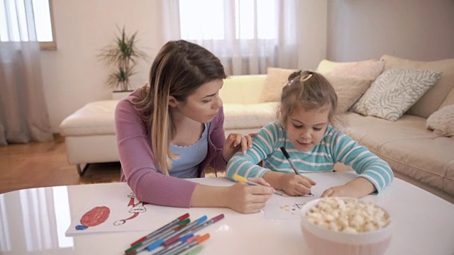 有创意的小女孩和她的妈妈在家里的纸上画画。视频素材