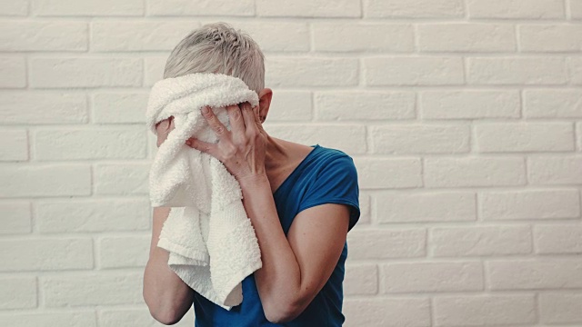 成熟的女人在家里运动训练后用毛巾擦汗。视频素材