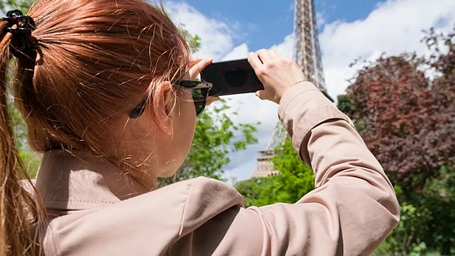 一个女人走在巴黎的街道上，拍着埃菲尔铁塔的照片视频下载