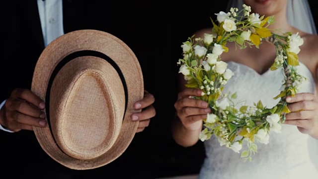 婚礼主题，新娘和新郎手持一顶帽子和花环。视频下载