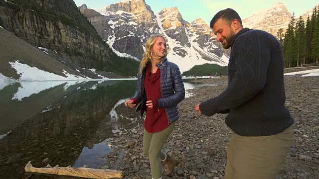 一对夫妇在美丽的山湖上跳石头视频素材