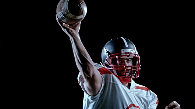 一名身穿白色运动衫的美国足球运动员在黑色背景上投球视频下载