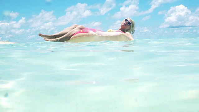 一个金发女人漂浮在马尔代夫的海洋里视频下载