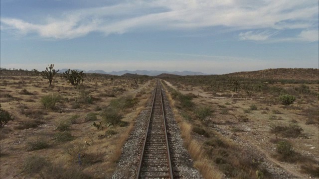 从火车后面加工钢板。在前景中看到火车轨道。沙漠里有仙人掌和灌木。视频下载