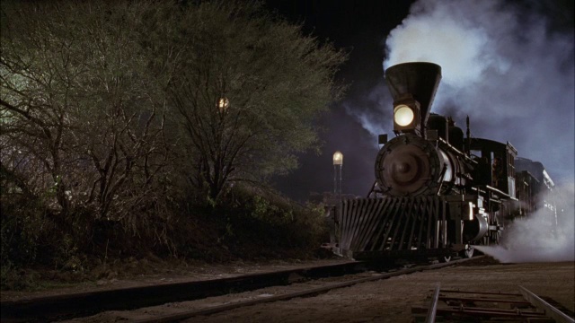 蒸汽机车或火车停靠时的中等角度。看到打开前灯。看火车冒烟了。看火车前进。看火车从右向左行驶。视频素材