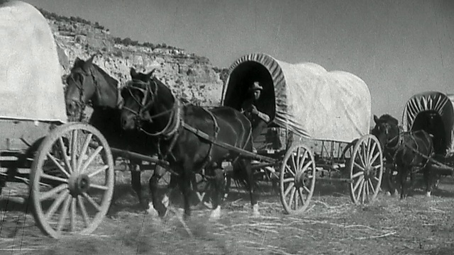 广角摄影机拍摄的再现有掩护的马车队与牛仔在马背上视频素材