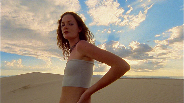 低角度中拍摄的女人在海滩上摆姿势在日落视频素材