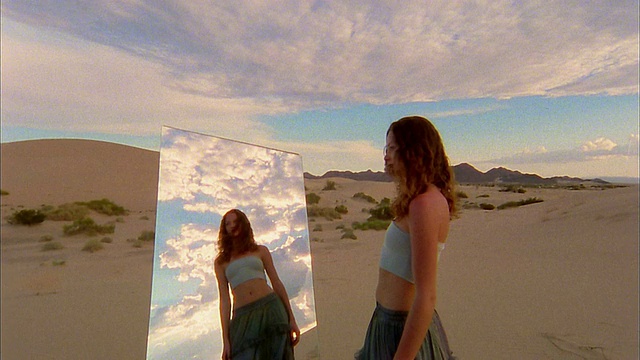 慢动作中镜头镜子在沙漠与反射的女人走向它/女人看反射视频素材