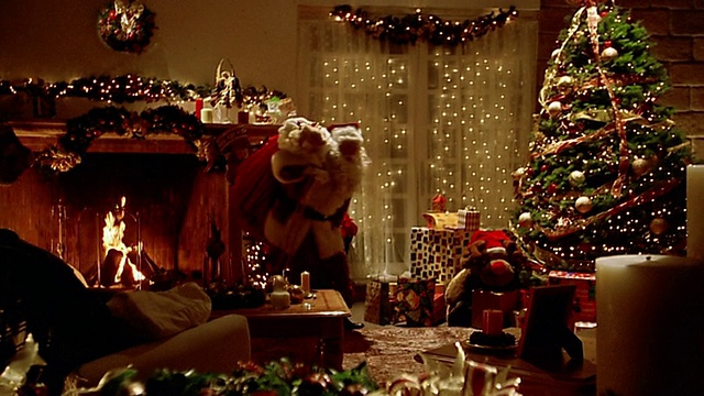 大镜头圣诞老人和一袋玩具靠近圣诞树/放大在打电话/躲避光视频下载