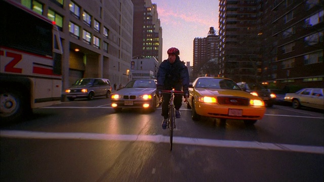 宽镜头跟踪拍摄自行车信使骑在车道之间的交通黄昏/纽约视频素材