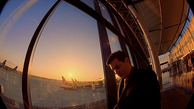 日出或日落时，在机场窗口附近使用掌上电脑的中型镜头商人视频下载