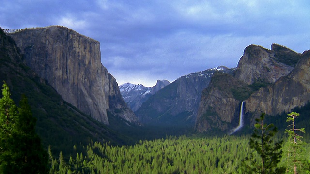 宽镜头约塞米蒂山谷与山脉和瀑布的背景/约塞米蒂国家公园，加利福尼亚州视频下载