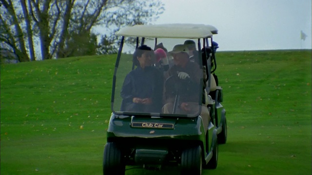 在高尔夫球场上开着高尔夫球车下山的夫妇视频素材