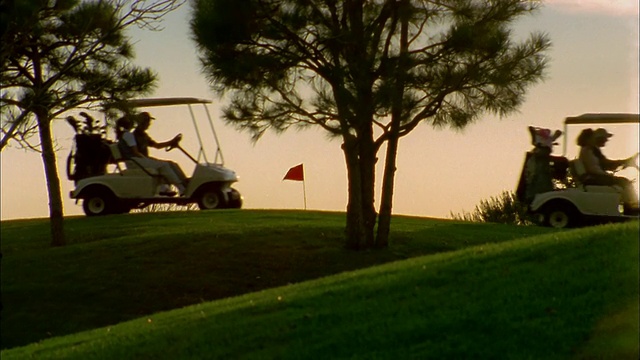 在日落时分驾驶高尔夫球车越过高尔夫球场地平线的夫妇视频素材