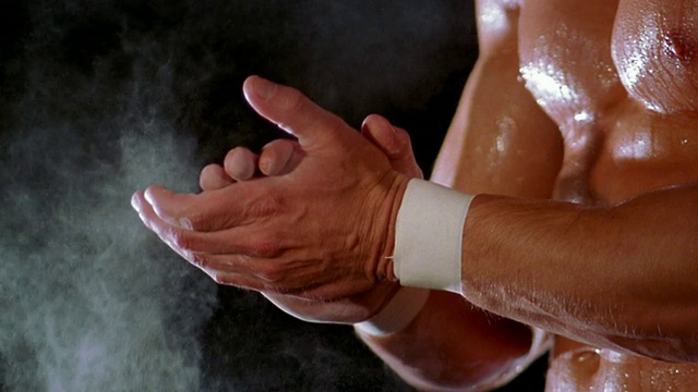 赤裸上身的举重运动员在双手之间拍粉笔视频素材