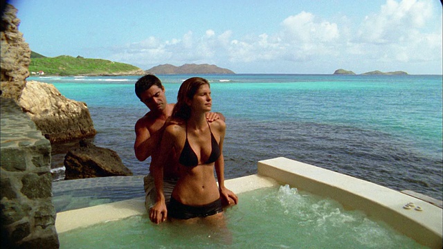 中镜头倾斜的女人接受按摩从男人在热水浴缸俯瞰大海视频素材