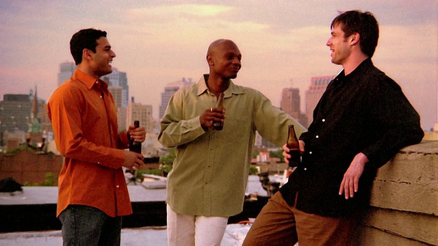 在纽约的屋顶上，三个年轻人一边喝着啤酒一边聊天视频素材