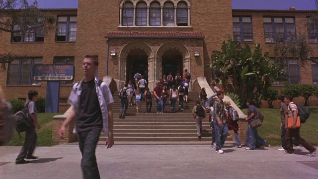 广角拍摄的一群学生进入和走出一个高中校园的入口。视频素材