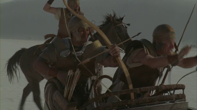 一名罗马士兵骑着战车穿越沙漠，一边射箭。视频下载