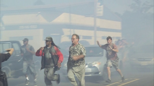 警察指挥惊慌的人群穿过烟雾弥漫的城市街道。视频下载