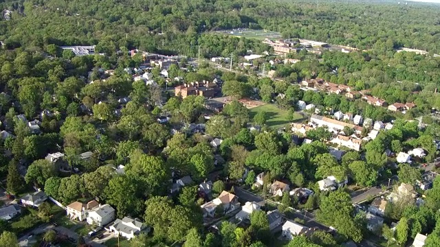 郊区社区房屋、树木和公园的天线。放大罗斯林高中，罗斯林高地，长岛，纽约。建筑物、街道、棒球场、停车场、足球场和网球场清晰可见。运动场地。视频素材