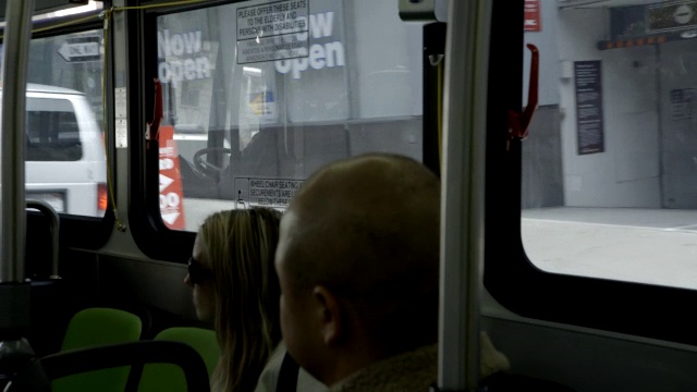 中等角度的乘客在公共汽车上，驾驶通过城市街道。视频素材