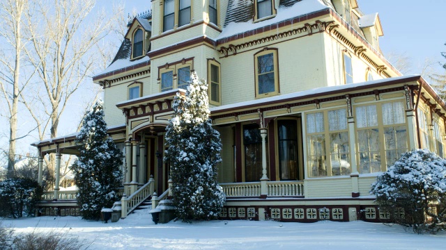 中角多层雪覆盖的维多利亚房屋。可见树木和树枝。视频素材