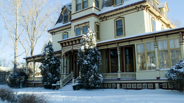 中等角度的雪覆盖多层维多利亚房屋。可见树木和树枝。视频素材