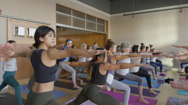 美国犹他州，瑜伽课上表演武士姿势的中慢动作平移镜头视频下载