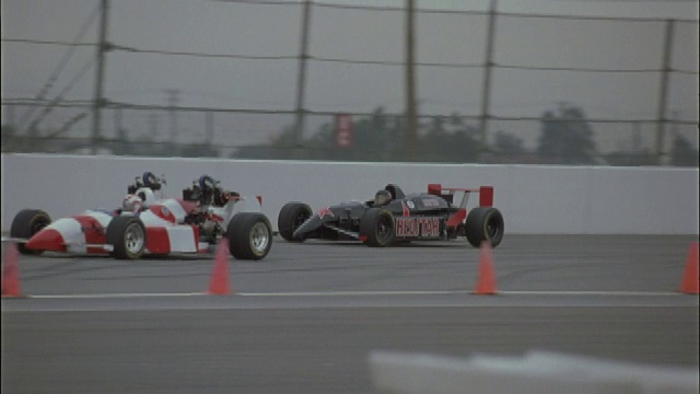 两辆一级方程式赛车在赛道上行驶，一辆向反方向旋转。视频下载