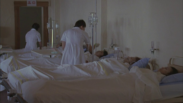 一个病人躺在医院的病床上，护士照料他。视频素材