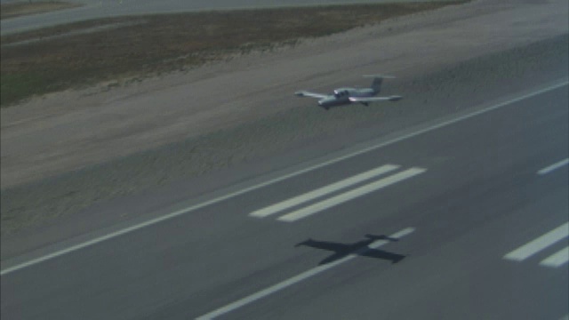 一架小型私人飞机在田野上空飞行，在机场跑道上着陆，然后又起飞。视频素材