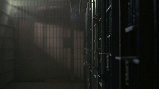 在南非一所监狱昏暗的走廊上，一个囚犯的胳膊和他的香烟冒出的烟雾充满了黑暗。视频素材