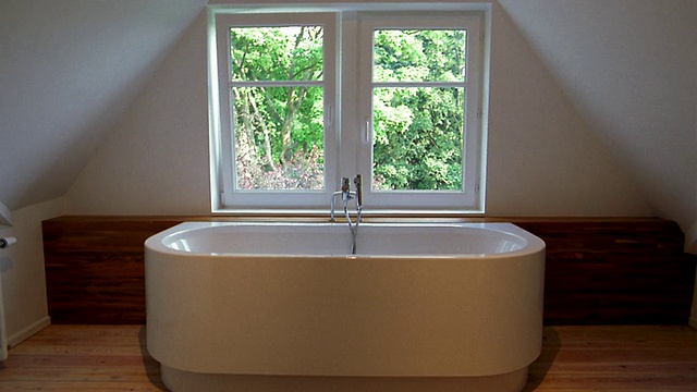 中等镜头的浴室配有木制水槽和镜子，浴缸，木地板+窗户，背景中有树视频素材