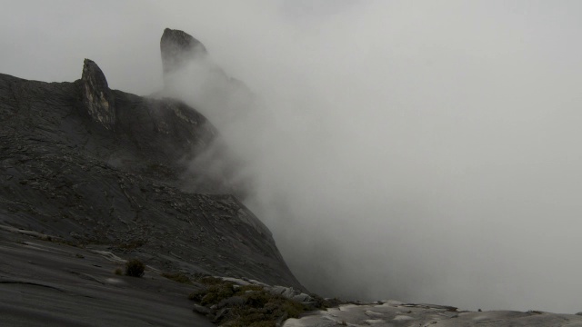 在婆罗洲基纳巴卢山，时断时落的云笼罩着岩石山峰视频素材