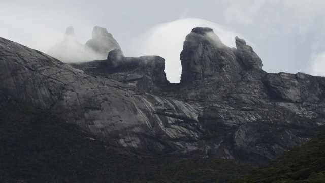 在婆罗洲基纳巴卢山的岩石山峰上，流逝的云滚滚而过视频素材