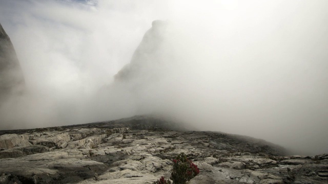 在婆罗洲基纳巴卢山，时断时落的云笼罩着岩石山峰视频素材