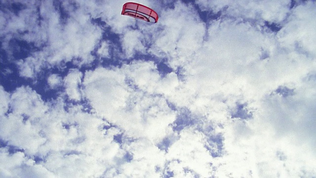 慢动作低角度男性风筝冲浪者在半空中对抗云和蓝天视频素材