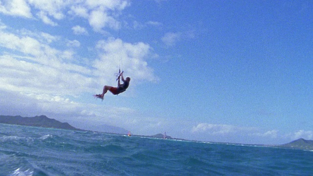 慢动作低角度男性风筝冲浪者在半空中，降落在水/瓦胡岛，夏威夷视频素材