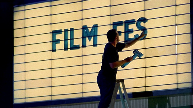 一名中等身材的男子在电影院的招牌上写着字/西雅图，华盛顿视频素材