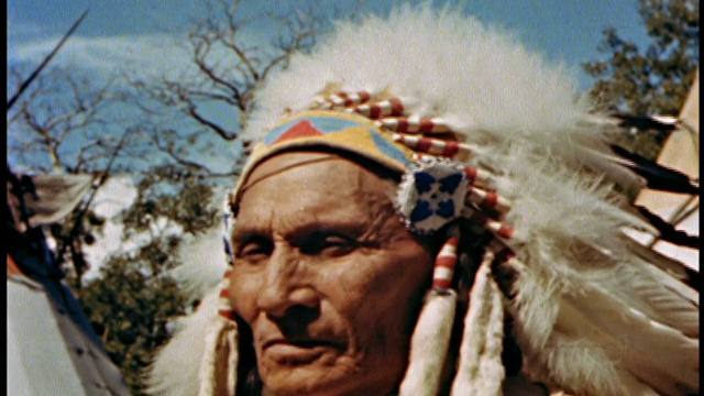 近距离观察戴着头饰/羽毛/转向看CAM / AUDIO的老印第安人视频下载