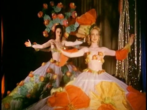 中等镜头的舞者走上台，穿着精致的裙子，戴着大花和头饰，双臂张开视频素材