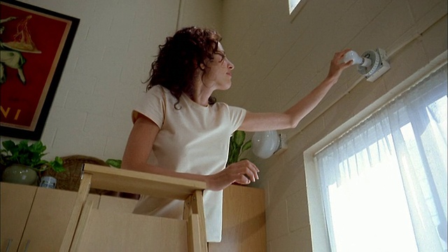 低角度中拍摄女人在梯子上换灯泡窗户上方视频下载