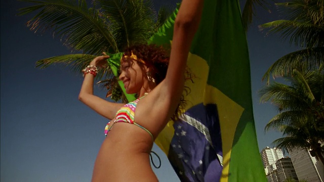 低角度的女人在比基尼微笑和挥舞巴西国旗视频素材