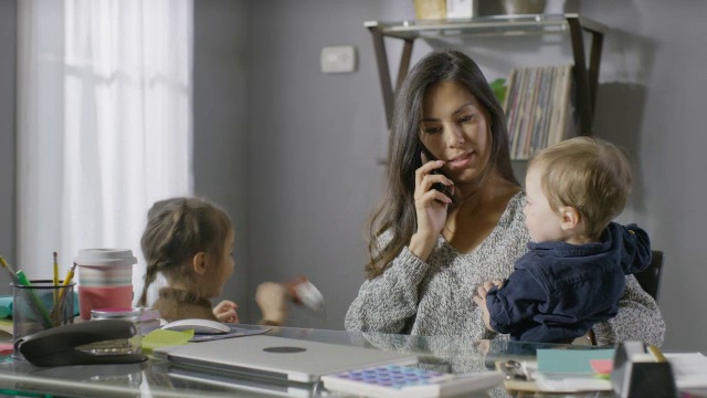 中等平移拍摄忙碌的母亲打电话被孩子打断/雪松山，犹他州，美国视频素材