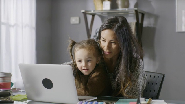 中等平移的照片微笑的母亲和女儿使用笔记本电脑/雪松山，犹他州，美国视频素材