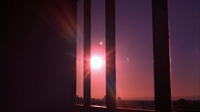摄影车通过带有垂直百叶窗的办公室窗户拍摄日落时的橘色视频下载