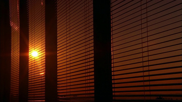 时光流逝，橘黄色的太阳透过办公室窗户的百叶窗落下视频素材